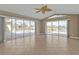 Bright living room featuring tiled floors, a ceiling fan, and multiple sliding glass doors with views of the pool and lake at 9428 Bandera Ln, Port Charlotte, FL 33981