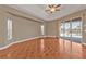 Spacious main bedroom featuring wood-look tile floors, ceiling fan, a sliding glass door, and views of the pool and canal at 9428 Bandera Ln, Port Charlotte, FL 33981