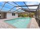 Inviting screened-in pool with clear blue water, surrounded by brick and lush greenery at 9505 Delray Dr, New Port Richey, FL 34654