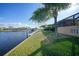 Waterfront backyard with a private dock and lush green lawn by a house, perfect for enjoying outdoor living at 1200 Winward Ct, Punta Gorda, FL 33950