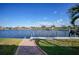 Waterfront backyard with dock, lush green grass, and a serene view of the water and neighborhood at 1200 Winward Ct, Punta Gorda, FL 33950