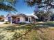 Exterior view of a well-maintained home with mature trees, a screened lanai, and cozy outdoor seating area at 1286 Green Oak Trl, Port Charlotte, FL 33948