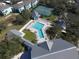 Aerial view of a community pool surrounded by lounge chairs and lush landscaping, and the tennis court at 1286 Green Oak Trl, Port Charlotte, FL 33948