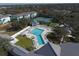 Aerial view of a community pool surrounded by lounge chairs and lush landscaping, and the tennis court at 1286 Green Oak Trl, Port Charlotte, FL 33948