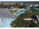 Aerial view of a community pool surrounded by lounge chairs, lush landscaping and the tennis court at 1286 Green Oak Trl, Port Charlotte, FL 33948