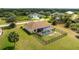 Drone shot of a home showing a screened-in pool and wrought iron fence, with a large backyard and blue skies at 13157 Ridgely Cir, Port Charlotte, FL 33981