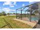 Backyard view of a screened-in pool and patio area with stone landscaping and wrought iron fence at 13157 Ridgely Cir, Port Charlotte, FL 33981