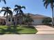 Inviting single Gathering home with a two-car garage, terracotta tile roof, and beautifully landscaped front yard with palm trees at 1453 Wren Ct, Punta Gorda, FL 33950