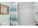 Bathroom featuring bathtub with shower curtain, tiled walls, and wooden mirror at 150 Harborside Ave # 122, Punta Gorda, FL 33950