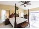 Comfortable bedroom features a large four-poster bed, dresser, and sliding glass doors to outdoor patio at 19179 Aviation Ct, Port Charlotte, FL 33948