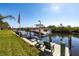 Waterfront dock and boat lift with American flag, lush lawn, and lovely creek view at 19179 Aviation Ct, Port Charlotte, FL 33948