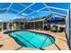 A refreshing pool is enclosed within a screened lanai that includes an umbrella table and outdoor furniture at 19179 Aviation Ct, Port Charlotte, FL 33948