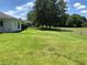 Spacious, grassy backyard with a chain-link fence, mature shade trees, and a view of the house's exterior at 223 Valdiva St, Punta Gorda, FL 33983