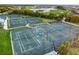 Aerial view of tennis courts with shade structures next to a community lake and golf course at 25197 Keygrass Ct, Punta Gorda, FL 33955