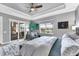 Cozy main bedroom showcases tray ceiling, fan, and sliding door access to the patio and outdoor kitchen at 25197 Keygrass Ct, Punta Gorda, FL 33955