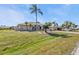 Inviting single-story home with a large lawn and an attached two-car garage, complemented by mature palm trees at 27566 Tierra Del Fuego Cir, Punta Gorda, FL 33983