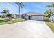 This single-story home includes an attached two-car garage, arched windows, mature landscaping, and a well-maintained lawn at 27566 Tierra Del Fuego Cir, Punta Gorda, FL 33983