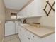 Functional laundry room with a white washer, dryer, ample cabinet space, and a utility sink at 27566 Tierra Del Fuego Cir, Punta Gorda, FL 33983