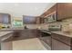 Modern kitchen featuring dark wood cabinetry, granite countertops, and stainless steel appliances at 2851 Verde Ter, North Port, FL 34286