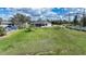 Spacious grassy backyard featuring a covered porch, neighboring homes, and blue skies at 3120 Wisteria Pl, Punta Gorda, FL 33950