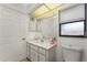 This bathroom features a white vanity, cabinet storage, and a window for natural lighting at 349 Grenada St, Port Charlotte, FL 33948