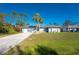 Landscaped single-story home with a long driveway, a two-car garage, and arched windows at 349 Grenada St, Port Charlotte, FL 33948