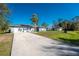 Long driveway view of a well-maintained home with a three-car garage and a lush front yard at 349 Grenada St, Port Charlotte, FL 33948