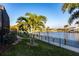 A waterfront backyard with manicured lawn, palm trees, and a private fence for an enchanting outdoor oasis at 3612 Licata Ct, Punta Gorda, FL 33950