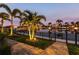 Serene water view at twilight with palm trees and elegant landscape lighting at 3612 Licata Ct, Punta Gorda, FL 33950