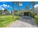 Home featuring a covered carport, lush lawn, and mature palm trees enhancing curb appeal at 3615 Sleepy Hollow Ln, Punta Gorda, FL 33950