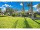 Charming single-story home featuring lush green lawn, mature trees, and a carport under a sunny blue sky at 3615 Sleepy Hollow Ln, Punta Gorda, FL 33950