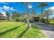 Home featuring a covered carport, lush lawn, and mature palm trees enhancing curb appeal at 3615 Sleepy Hollow Ln, Punta Gorda, FL 33950