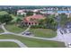 Aerial shot of the beautiful community clubhouse with golf course views, lush landscaping, and a red tile roof at 10256 Shadow Run Ct, Punta Gorda, FL 33955