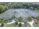 Overhead shot of well-lit tennis courts with green fencing, surrounded by palm trees and tropical landscaping at 10256 Shadow Run Ct, Punta Gorda, FL 33955