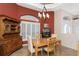 Dining room showcasing a red accent wall, charming hutch, window with shutters, and modern chandelier at 1217 Bobwhite Court, Punta Gorda, FL 33950