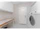 Bright laundry room with white cabinets, folding table, and a modern washing machine at 1217 Bobwhite Court, Punta Gorda, FL 33950