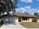 Charming home with a two-car garage, light yellow paint, an arched entryway, and a well-maintained lawn at 20408 Andover Ave, Port Charlotte, FL 33954