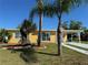 Charming yellow single-story home with mature landscaping, palm trees, and a carport at 21938 Catherine Ave, Port Charlotte, FL 33952