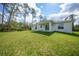 Expansive backyard with green grass and the home's back facade at 23254 Stelling Ave, Port Charlotte, FL 33980