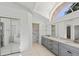 Bright bathroom with double vanity, glass shower, and soaking tub under vaulted ceiling with skylight at 24344 Penhollow Ct, Punta Gorda, FL 33955