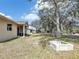 Spacious backyard with mature trees, a fire pit, and a covered patio with outdoor seating at 2822 Logsdon St, North Port, FL 34287