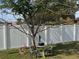Cozy seating area in the backyard beneath a tree, surrounded by a white fence at 3289 Pellam Blvd, Port Charlotte, FL 33948