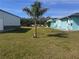 Exterior view of a home with a manicured lawn and mature palm trees at 3289 Pellam Blvd, Port Charlotte, FL 33948