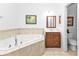 Bright bathroom featuring a corner soaking tub with tan tile surround and oak vanity at 4504 Vaquero St, North Port, FL 34286