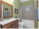 Bathroom with green walls featuring tile floors, a shower-tub combo, and wood vanity at 4504 Vaquero St, North Port, FL 34286