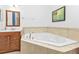 Bright bathroom featuring a corner soaking tub with tile surround and a wooden vanity at 4504 Vaquero St, North Port, FL 34286