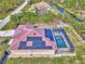 Aerial view shows the red metal roof, solar panels, and screened-in pool in the back yard at 8230 Agate St, Port Charlotte, FL 33981