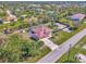 An aerial view of a home with a red metal roof, screened pool, boat parking, and lush green landscaping at 8230 Agate St, Port Charlotte, FL 33981
