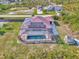 Aerial view of a home with screened-in pool, red metal roof, solar panels, and fenced boat parking area at 8230 Agate St, Port Charlotte, FL 33981