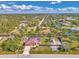 Expansive aerial shot of a community featuring mature trees, water features, and a home with a metal roof at 8230 Agate St, Port Charlotte, FL 33981